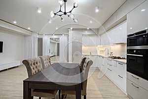 White spacious kitchen interior with dining room table and chairs