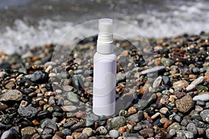 White spay bottle standing at the ocean coast