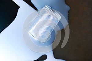 White spilled milk with the glass on the black background