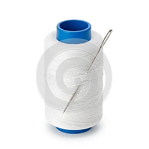 White sewing thread spool with a silver needle inserted into the top on a white background