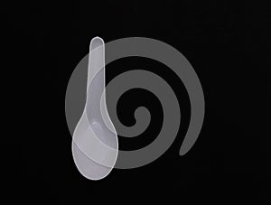 A white spoon plastic on black.