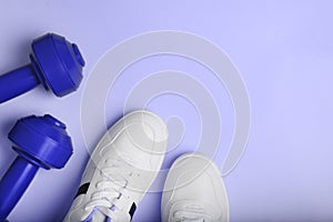 White sport sneakers shoes and blue dumbbells on the blue background.