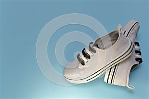 White sports sneakers on a light blue background.