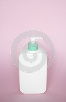 White square bottle with a cyan dispenser for liquid soap, shampoo, gel on pink background.