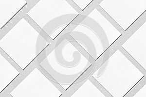 white square business card mockups lying diagonally on grey concrete background