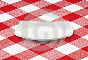 White square empty plate on red gingham tablecloth