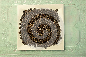 White square plate with a heap of coffee beans