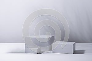 White square podiums in sunlight with shadow palm leaf in white space. Tropical showcase for cosmetic products, goods, shoes.