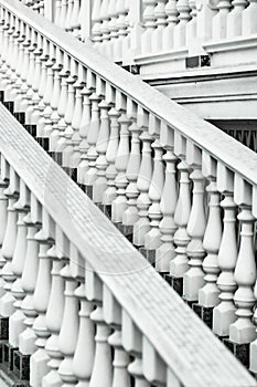 White staircase with balusters. Bright building with a beautiful staircase. Repetitive elements in architecture. Marble staircase