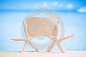 White starfish with blank retro photo on white sand beach, sky a