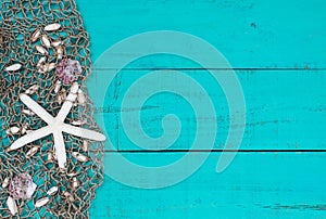 White starfish and shells in fish netting on teal blue wood beach sign