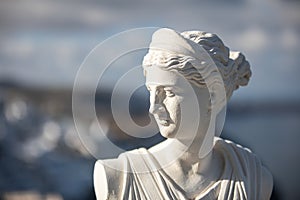 White statue of Artemis, Diana goddess with blurred greek cityscape