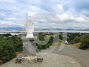 White statue of Saint Patrick at the start of foot path to the peak