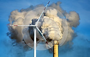 White steam cloud and smoke clouds rise from a high chimney into the blue sky