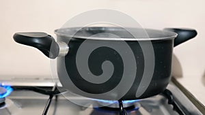 White steam rises from boiling water in a saucepan. Water boils in a saucepan