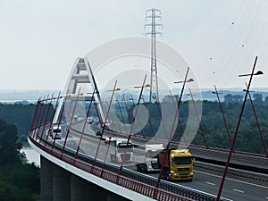 White steel bridge with traffic of several trucks and cars in morning light