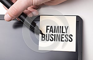 white sticker on the monitor in the office with text FAMILY BUSINESS and hand with marker