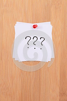 White Sticky Notes with Three Question Marks Pinned to the Wooden Message Board