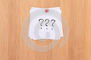 White Sticky Notes with Three Question Marks Pinned to the Wooden Message Board