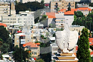 White stone eagle guards the gate to Bahai Gardens and overlooks the cityscape of Haifa