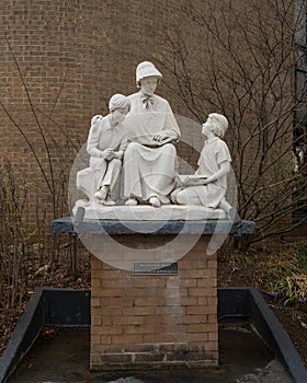 White stone sculpture of Saint Elizabeth Ann Seton teaching two children outside a school in Edmond, Oklahoma.