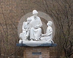 White stone sculpture of Saint Elizabeth Ann Seton teaching two children outside a school in Edmond, Oklahoma.
