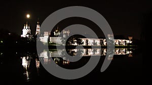 White stone wall of Novodevichy Convent, reflection in water of pond at night.