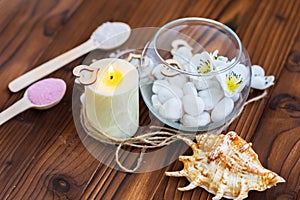 White stones in a glass vase, flowers and a big candle for spa and relaxation