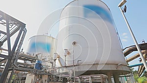 White storage tanks for liquids in a modern factory. Large storage tanks in the factory. Exterior of a modern factory.