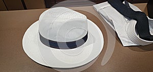 White straw Panama hat and plain shirt and black knit tie on menswear counter in store - Shopping for a man