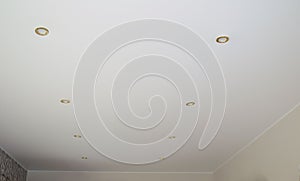 White stretch ceiling of the living room with lamp