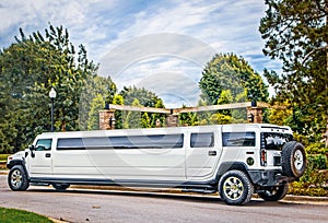 White stretch Limousine SUV parked on street in leafy area