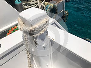 White strong durable thick fabric ship rope, a rope for the berth, a stop attached to the ship, a boat on the background of the bl