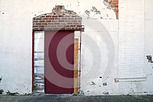 White stucco alley building red door exposed brick