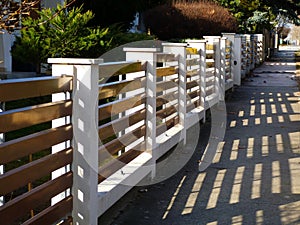 White stucco finished fence piers with horizontal brown metal slats