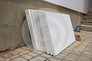 White styrofoam near the house,styrofoam sheets stacked to the wall for repair and insulation of the facade of the house