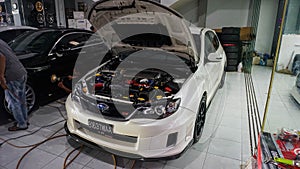 White Subaru WRX STI hatchback on car workshop showing the engine