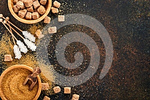 White sugar, cane sugar cubes, caramel in bamboo bowl on dark brown table concrete background. Assorted different types of sugar.