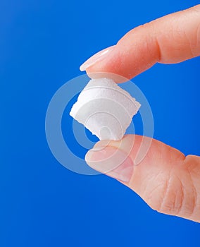 White sugar cube held between fingers