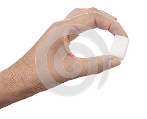 White sugar cube held between fingers  on white background. One lump of sugar.