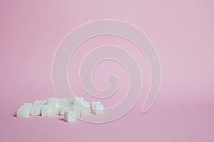 White sugar cubes on a pink background