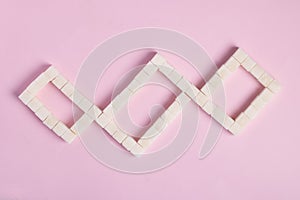 White sugar cubes on pink background. Top view. Diet unhealty sweet addiction concept photo