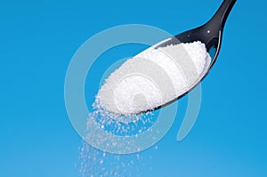 White Sugar spoon blue background.