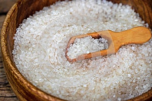 white sugar in wooden bowl, wooden scoop on old wooden background