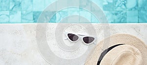 White sunglasses and hat near swimming pool in luxury hotel. Summer travel, vacation, holiday and weekend concept