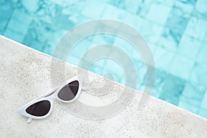 White sunglasses near swimming pool in luxury hotel. Summer travel, vacation, holiday and weekend concept