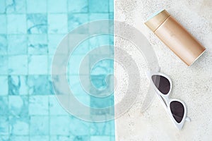 White sunglasses, sunscreen bottle and hat near swimming pool in luxury hotel. Summer travel, vacation, holiday and weekend