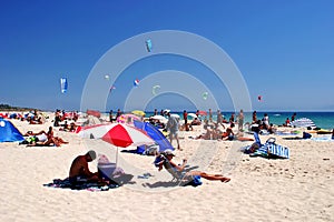 White, sunny, sandy beach full of kitesurfers in Tarifa, Spain photo