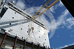 White superstructure with navigational bridge on the merchant container ship with cranes and hooks.