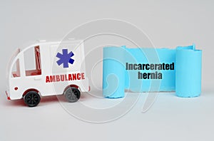 On a white surface, an ambulance and a blue paper sign with the inscription - Incarcerated hernia